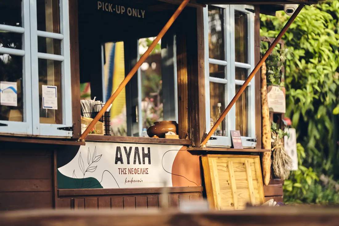 Avli tis Nefelis kiosk window with hand-painted sign
